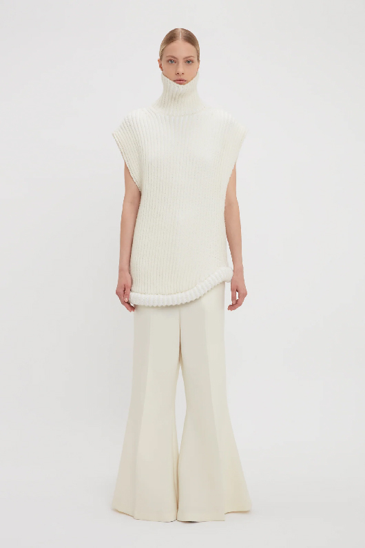 Women in white high neck sleeveless jumper and wide leg trousers 