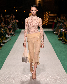Women in a beige top and beige skirt on the runway 
