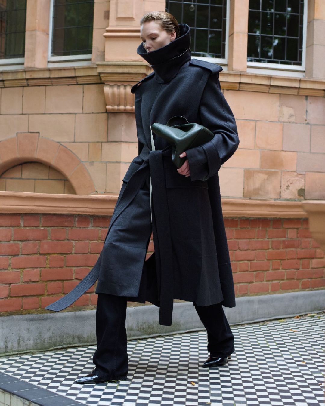 Women in grey trench coat with green bag 