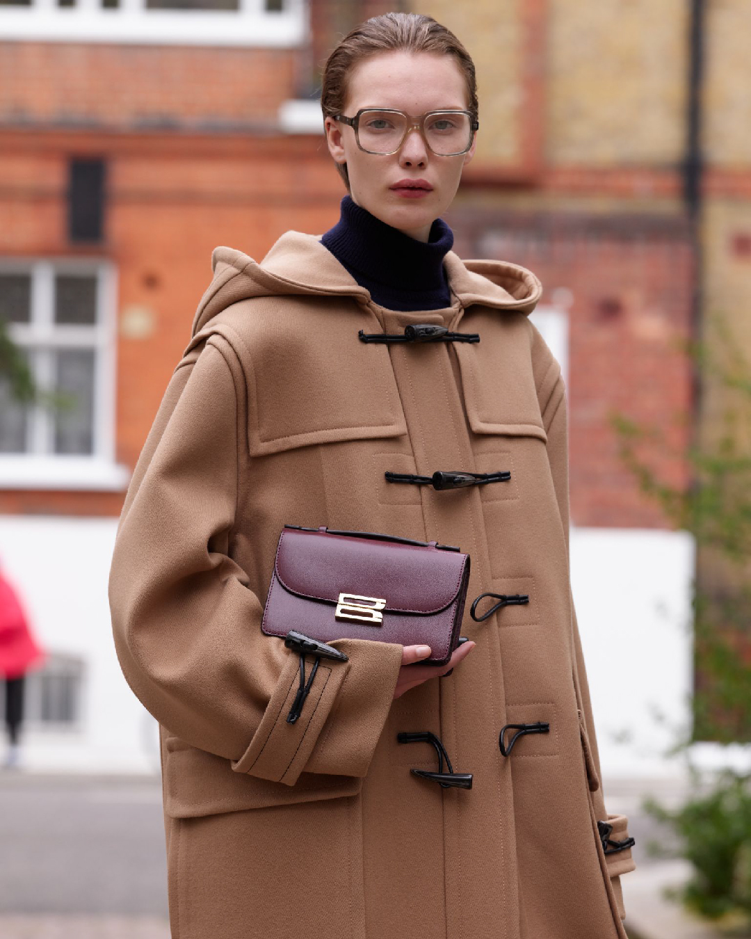 Women in brown coat with burgundy bag 