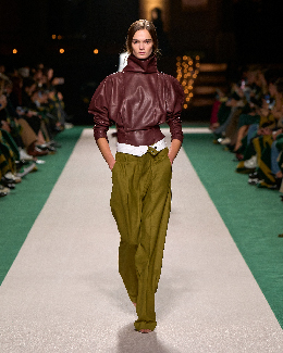 Women in green trousers and burgundy top on the runway 